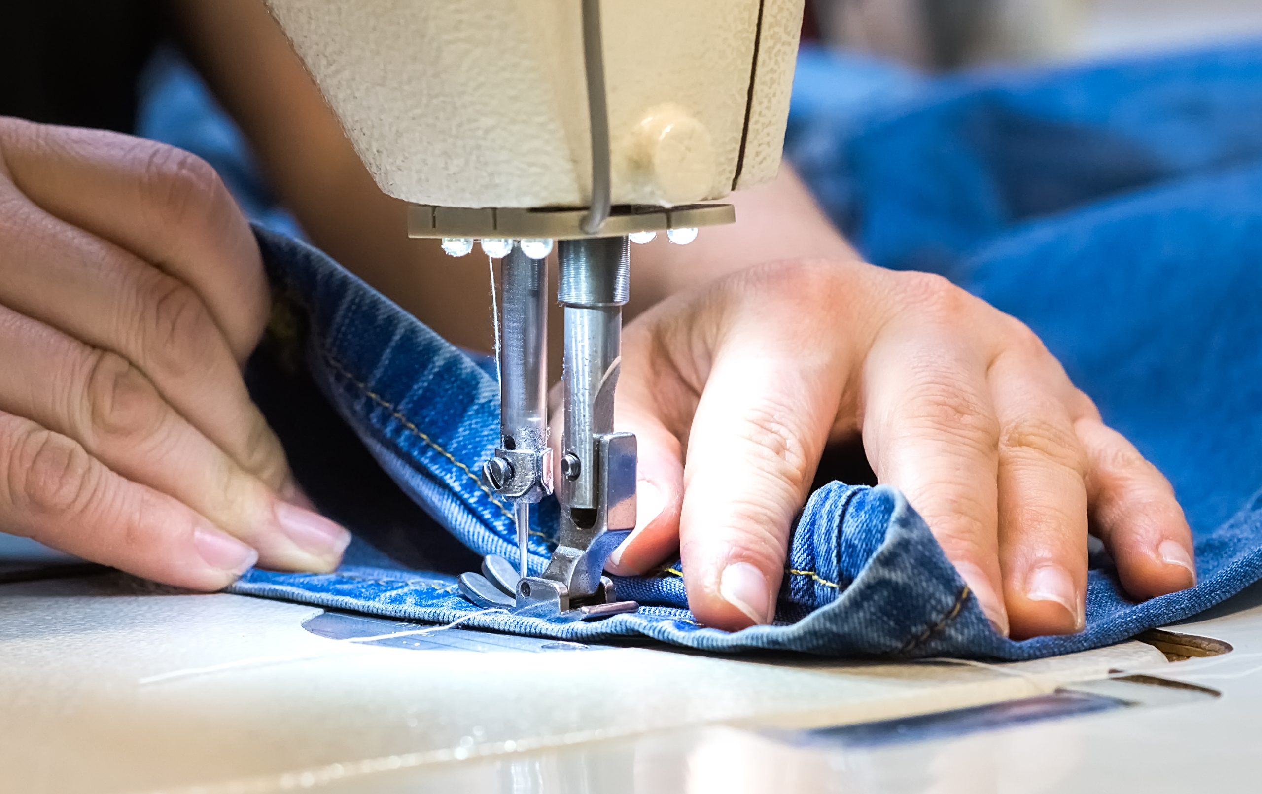 Hands Sewing Denim Fabric on a Machine
