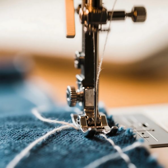 Close up view of a sewing machine needle stitching blue fabric creating textile art